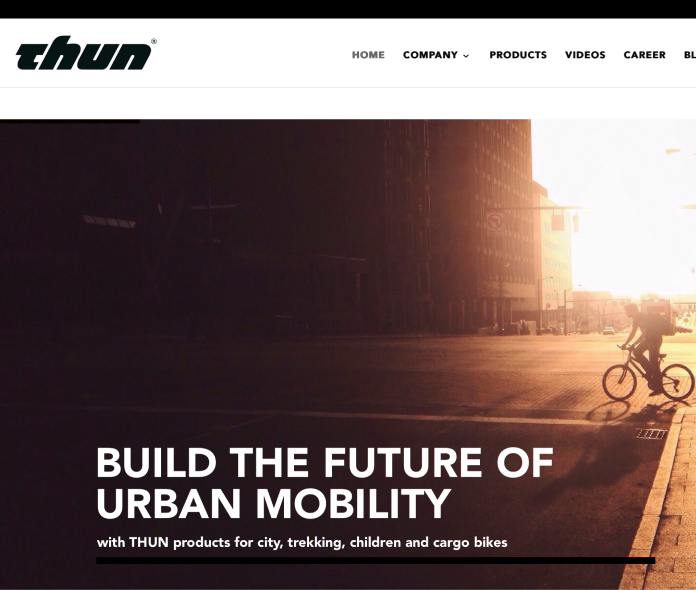 Das Coverbild der aktuellen THUN-Webseite mit einem Fahrrad vor dem Sonnenuntergang in einer Großstadt.